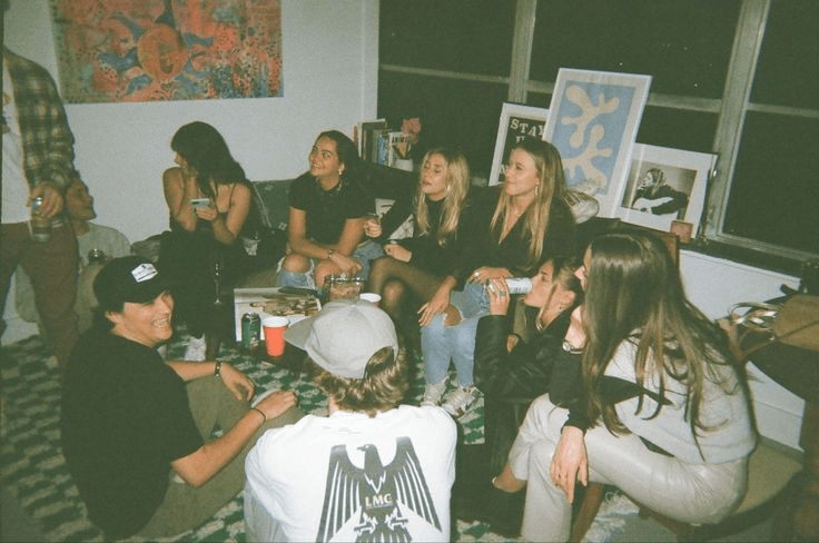 Un groupe de personnes assises ensemble dans une pièce, discutant et riant, avec des œuvres d'art visibles sur les murs. Colocation pour étudiants en Suisse.